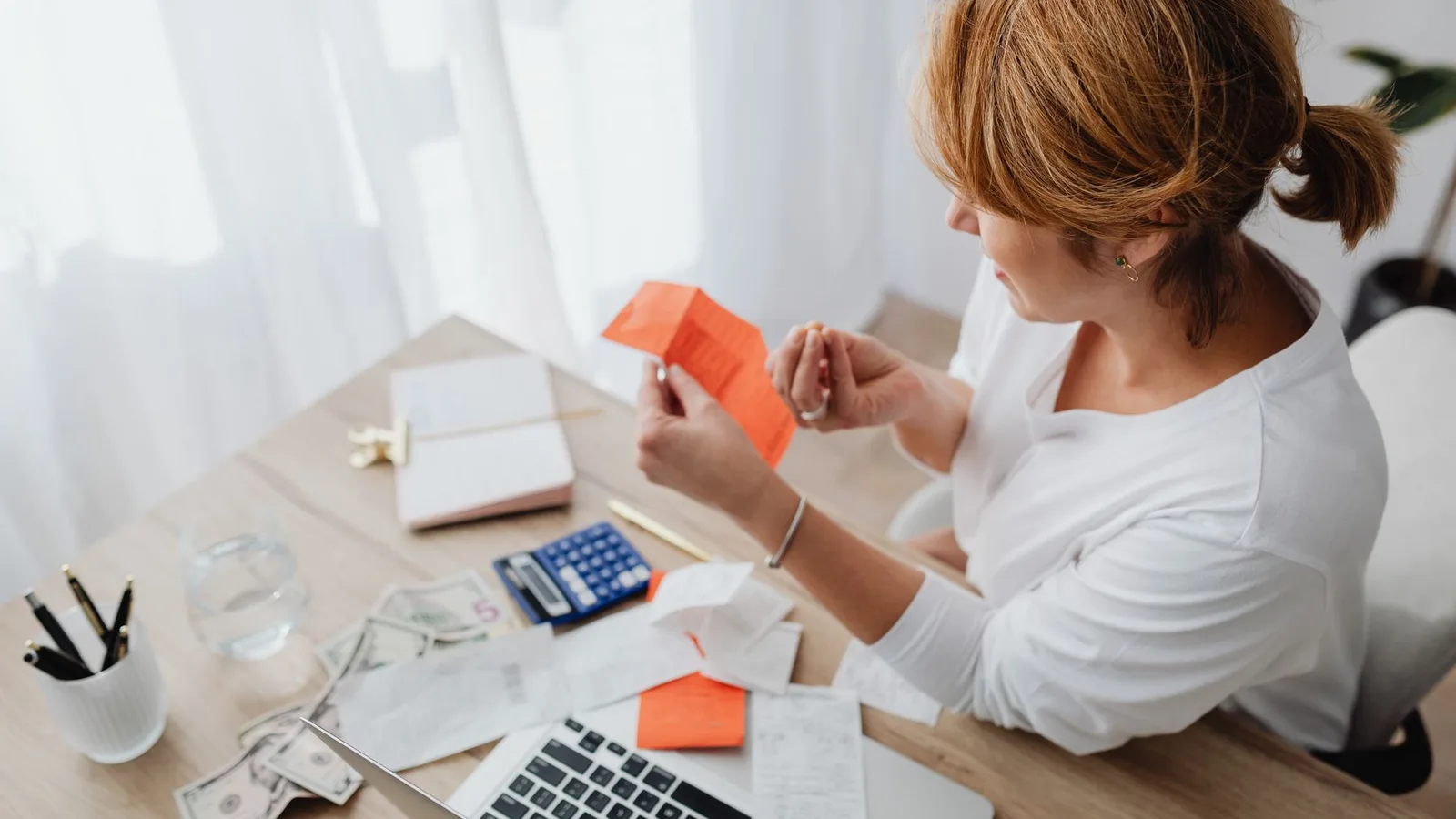 Woman reviewing receipts beside a calculator and laptop