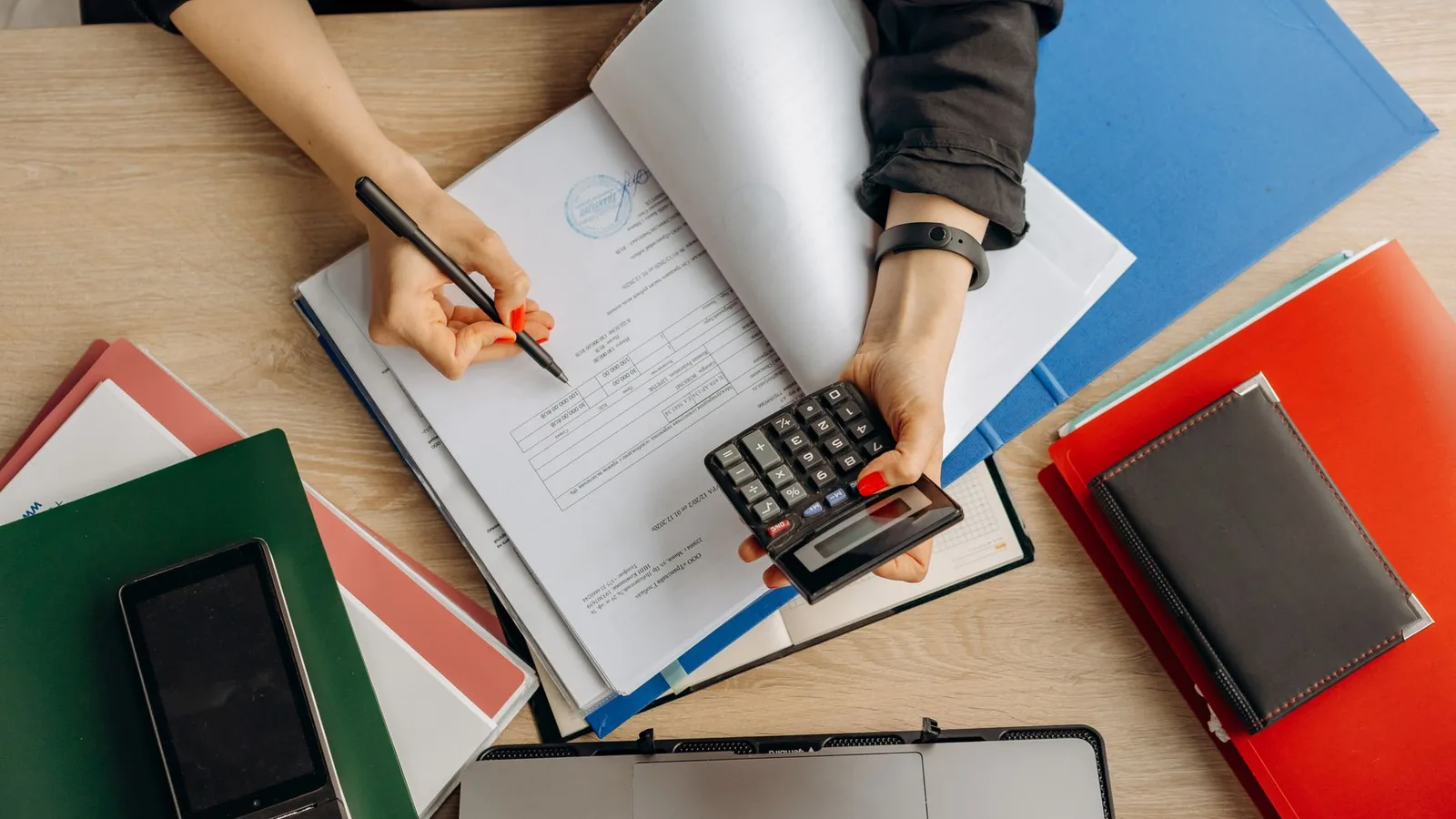 Hands reviewing financial documents with a calculator at a desk