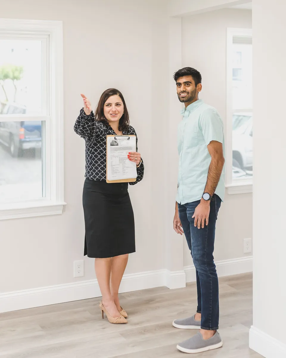 Real estate agent with a clipboard showing a bright, empty home to a buyer