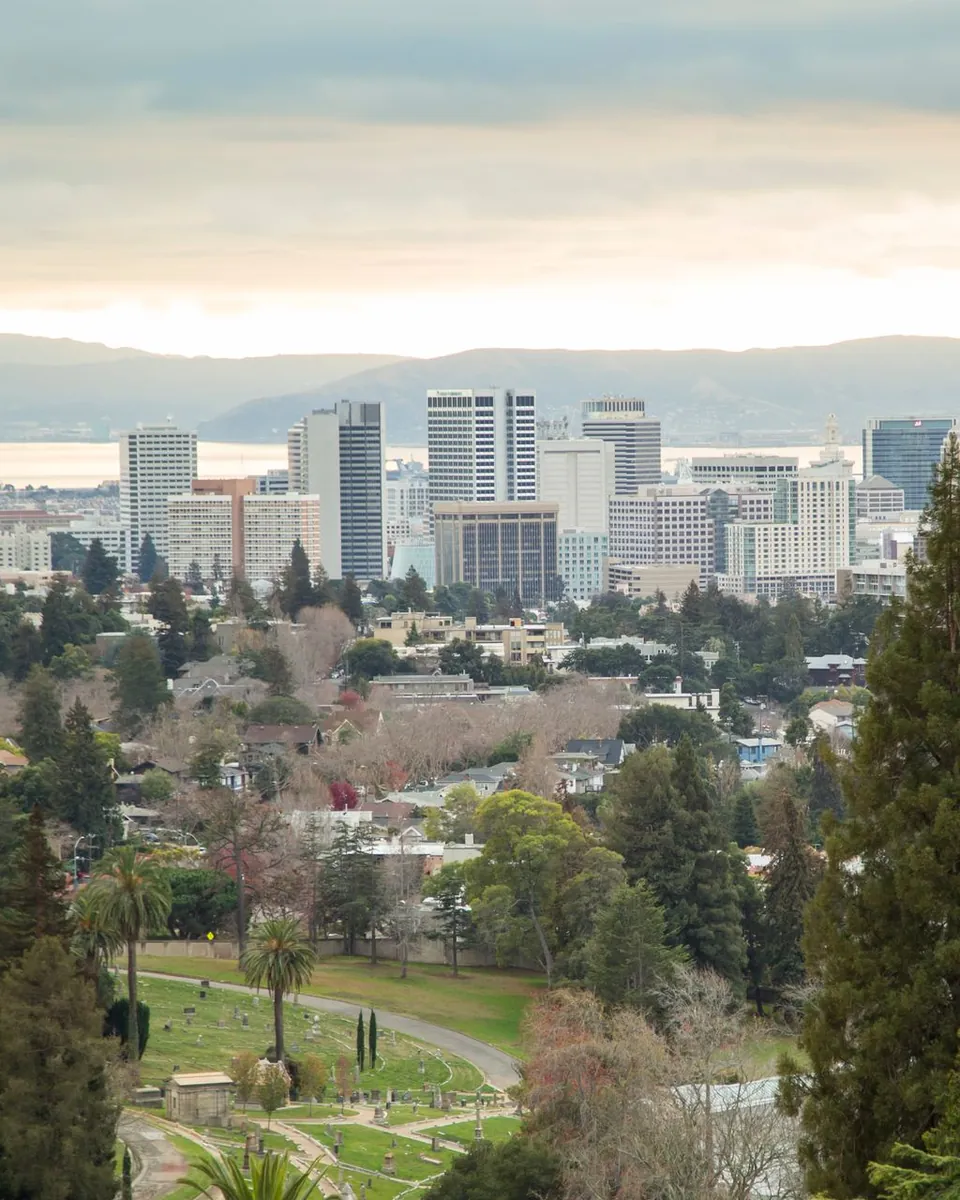 Downtown Oakland, CA skyline and the bay beyond tree-covered hills