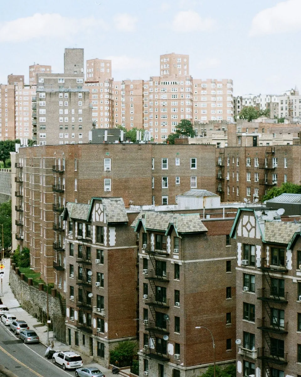 Brick apartment buildings and a winding road on a green hillside in the Bronx, NY