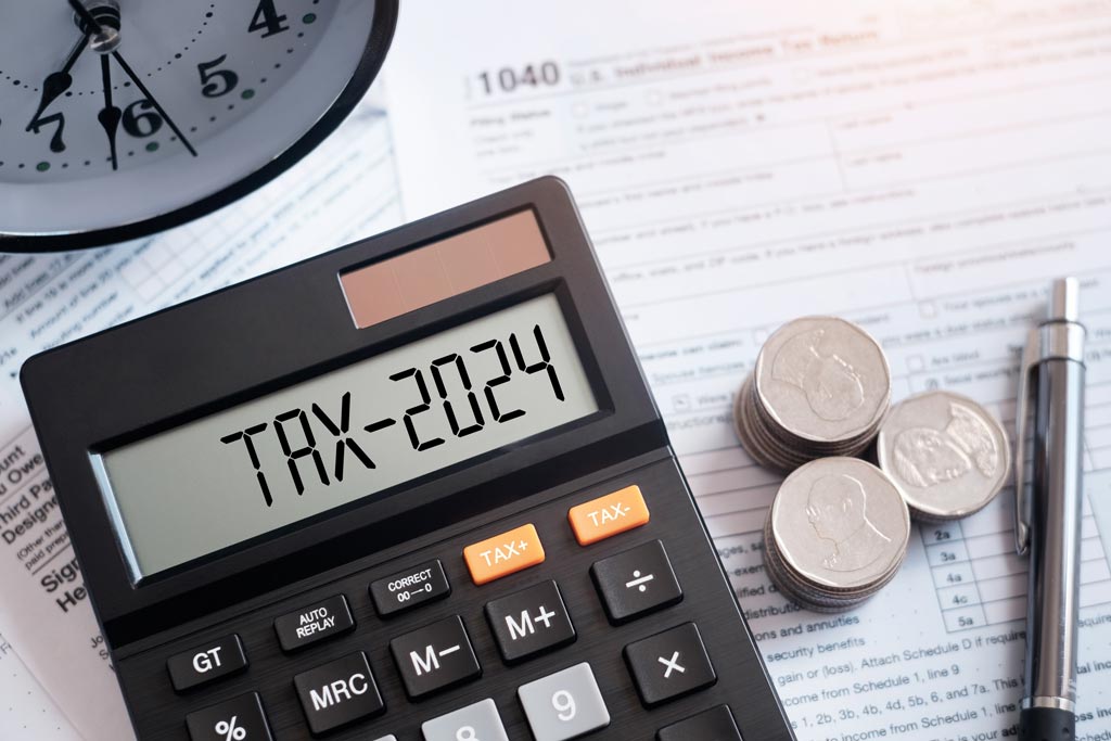 Closeup of calculator with words Tax 2024 in bold black print 