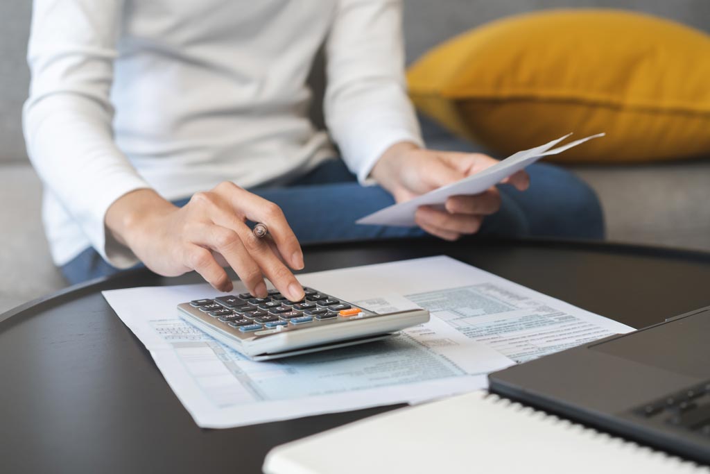 Young woman using calculator and checking deductions for IRS tax filing 