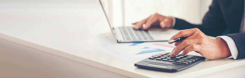 Closeup of male hands as a businessman works on his taxes on laptop 