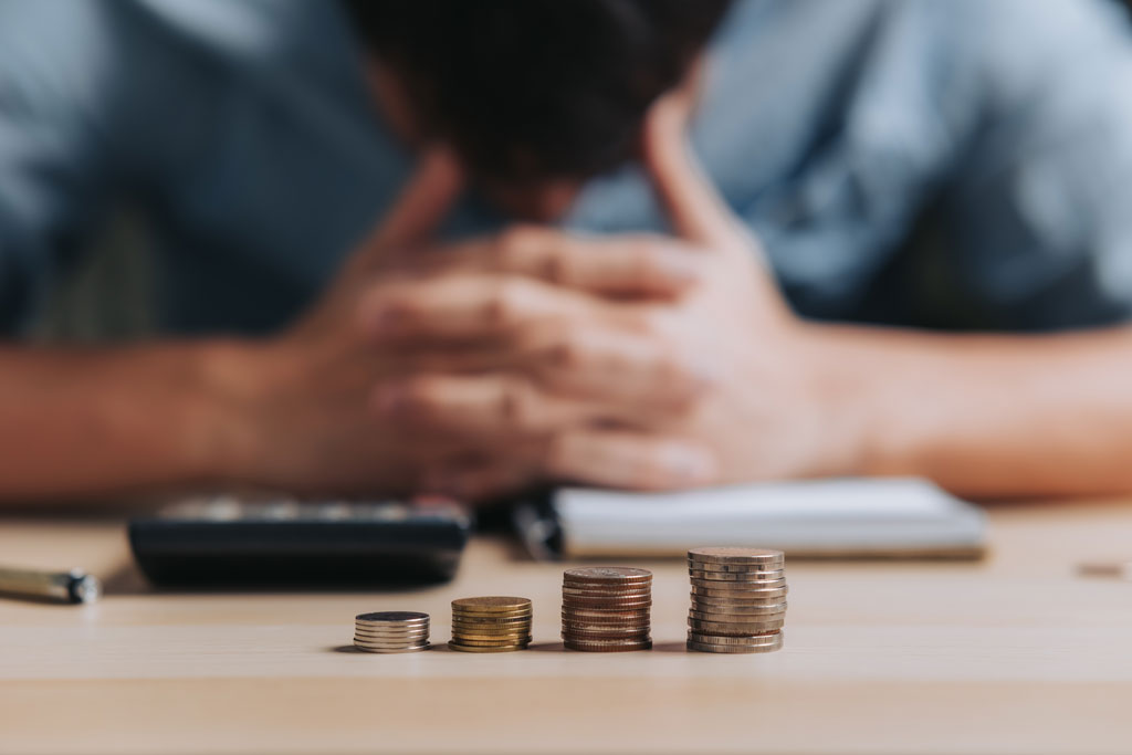 Male hands and calculator in background small stacks of change in foreground